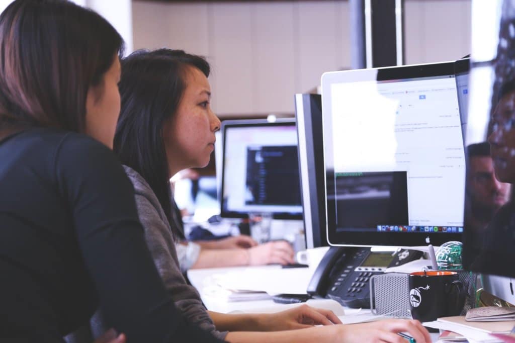 Two women analyzing data on computer