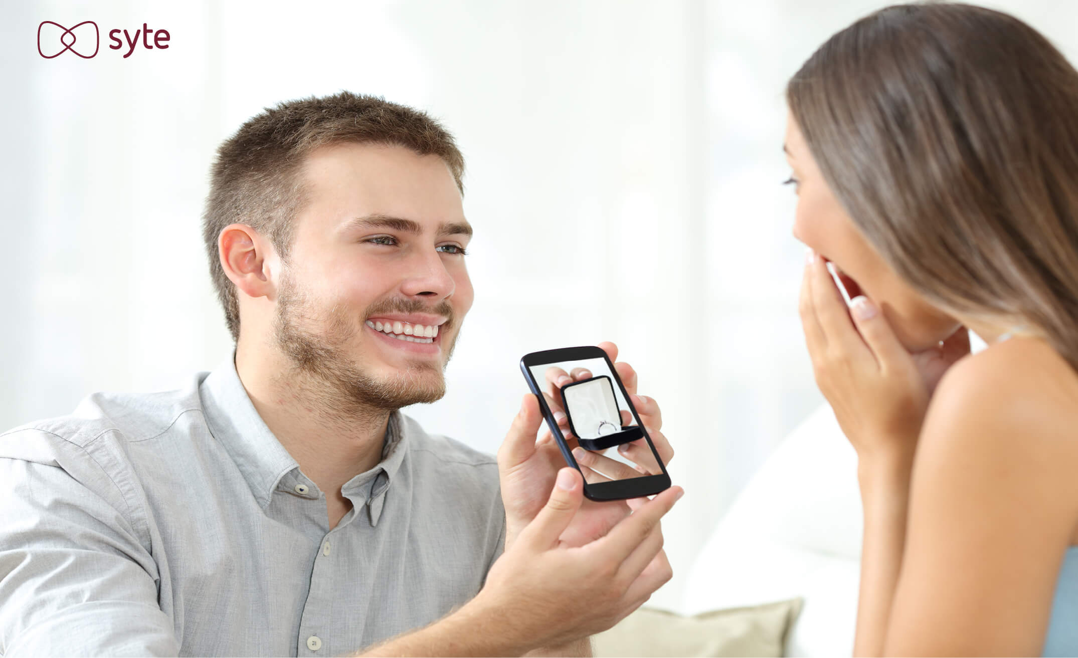 Product discovery for jewelry: A man asks a woman to marry him with a ring pictured inside a smartphone