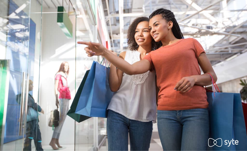 Two women point at a product display that has been tailored to consumer behavior and expectations