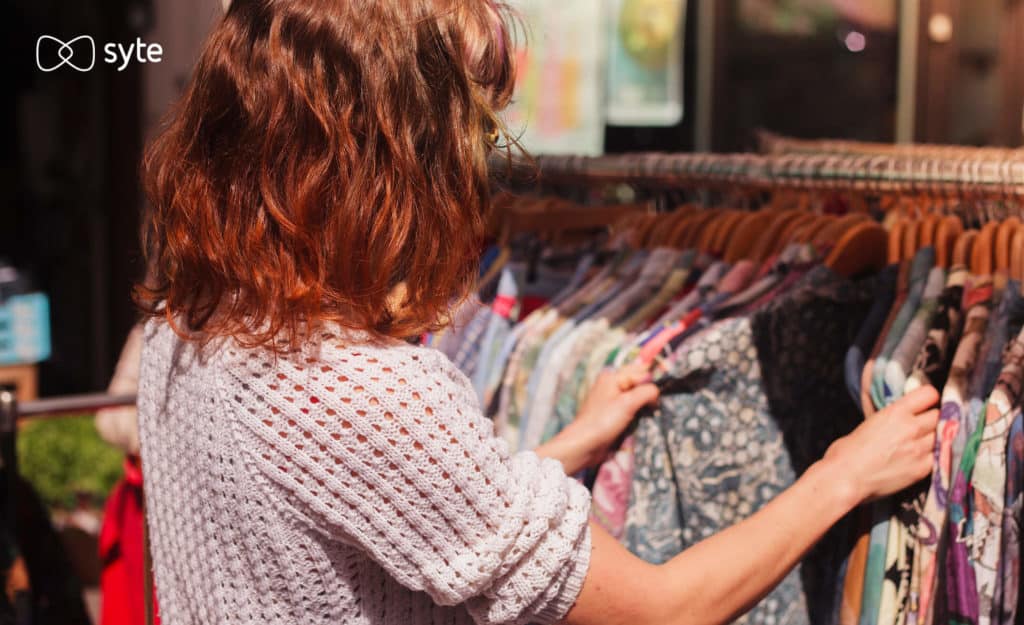 A woman searches through a vintage clothing rack. 