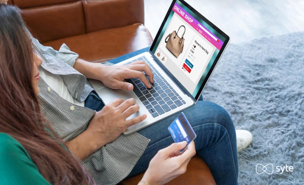 Couple sitting on couch with laptop and credit card out for purse purchase. 