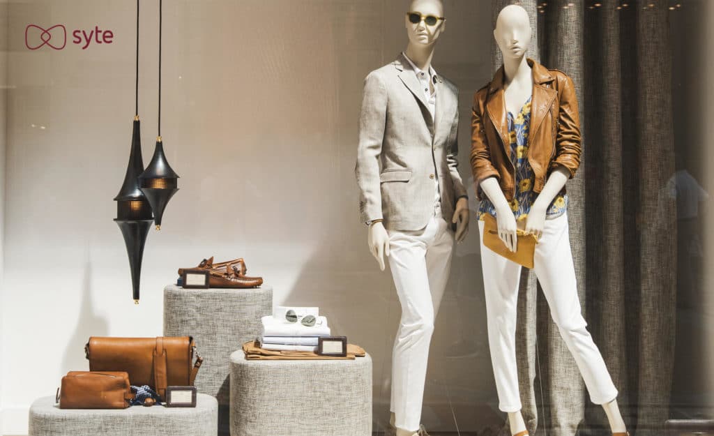 Example of lifestyle merchandising with a store display that includes two mannequins wearing different outfits next to a selection of bags, shoes, and other items.