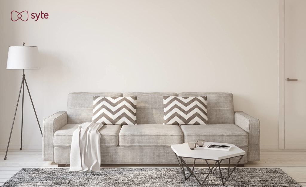 Picture of a fully furnished living room with a couch, pillows, lamp, blanket, rug, coffee table, and mugs.