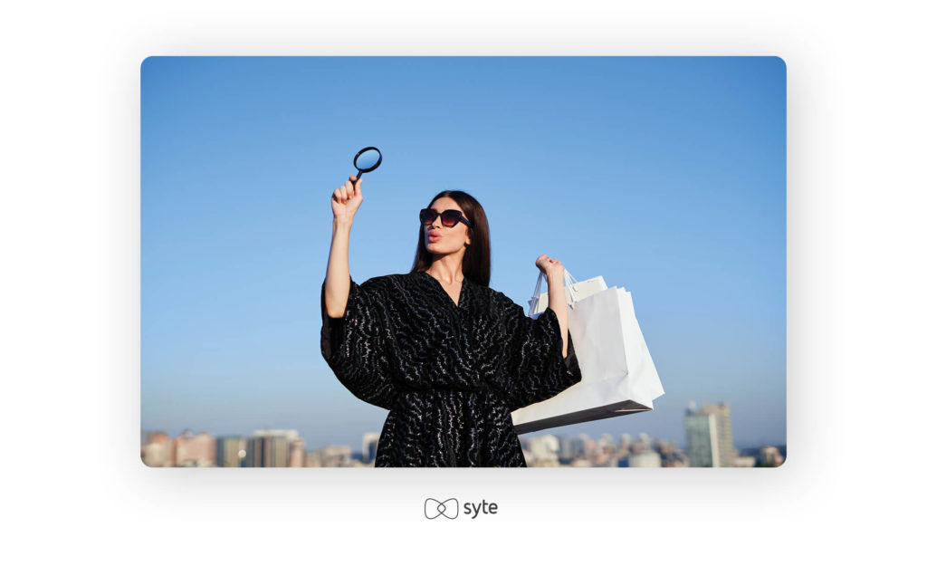 Girl with a magnifying glass and white shopping bags in an urban setting.