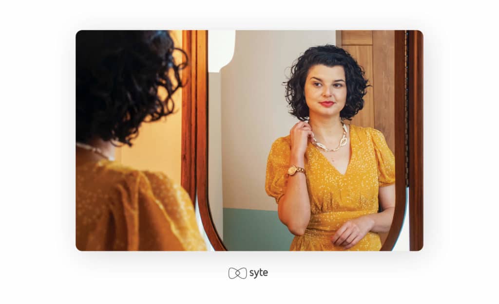 Woman adjusting her jewelry in front of a mirror.