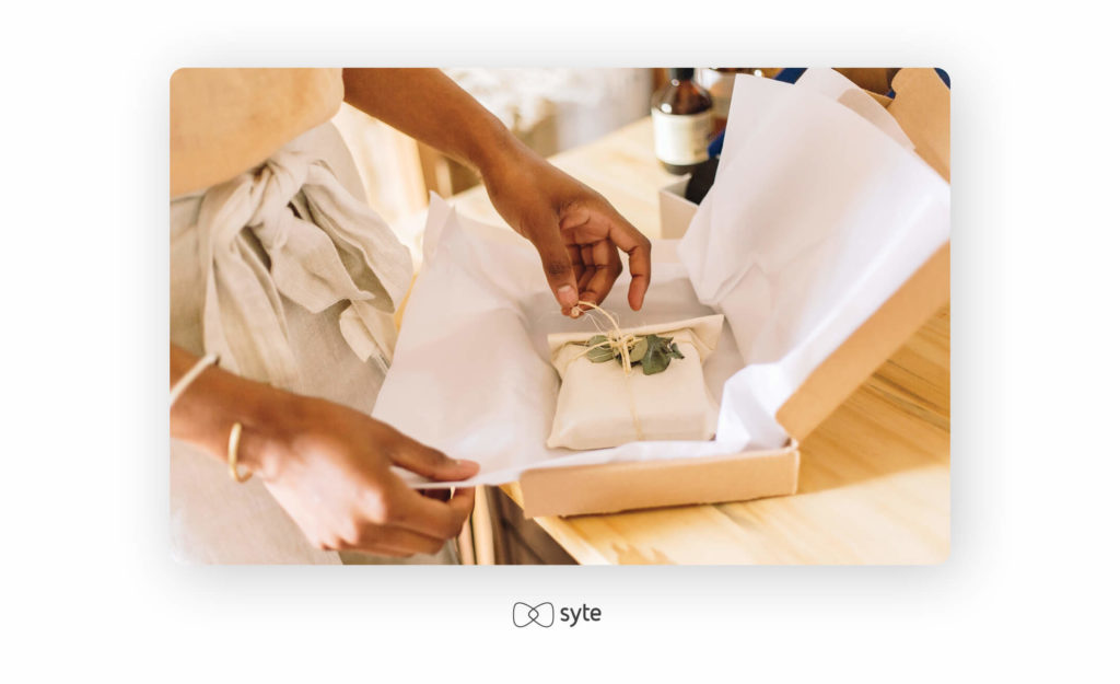 Closeup of woman packing order for online client in her office. Female hands wrapping thread on jewelry box for delivery.