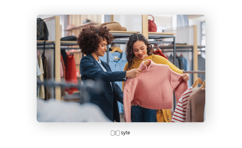 shop assistant showing a sweater to a customer