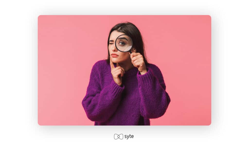 Woman looking pensively through a magnifying glass