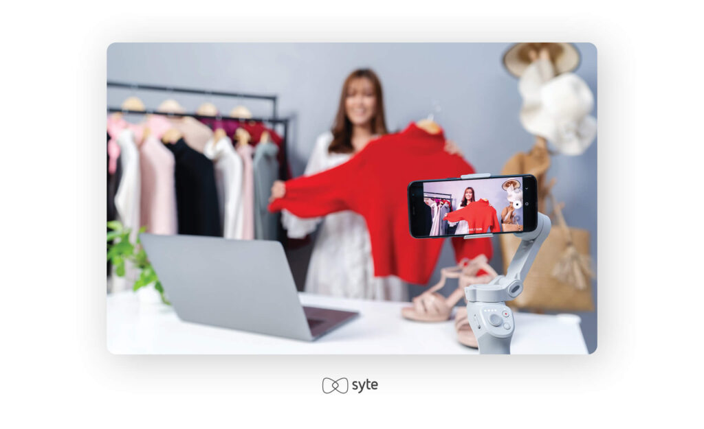 Woman holding a red sweater while being filmed