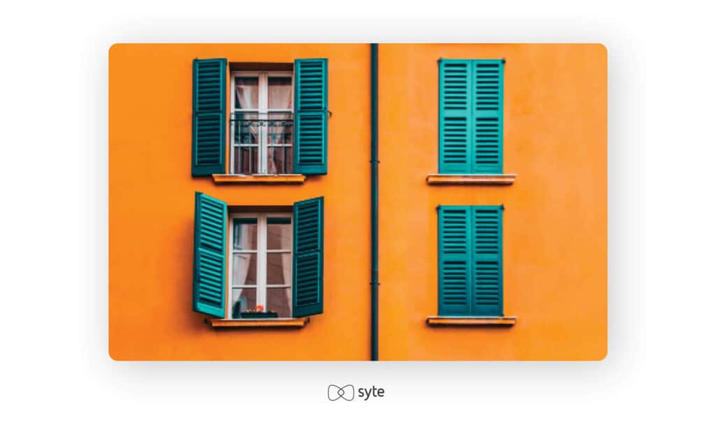 A building with open shutters on one side and closed shutters on the other.