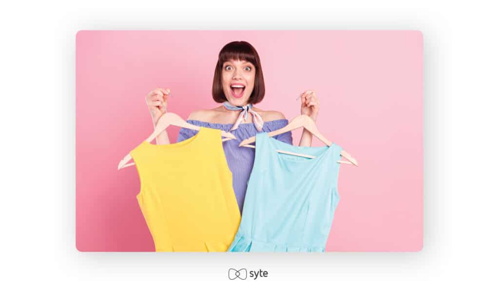 Happy woman holding two dresses in different colors.