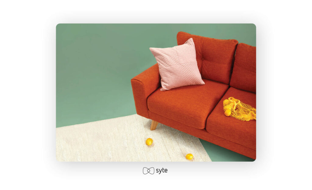 Orange couch with a pink cushion.