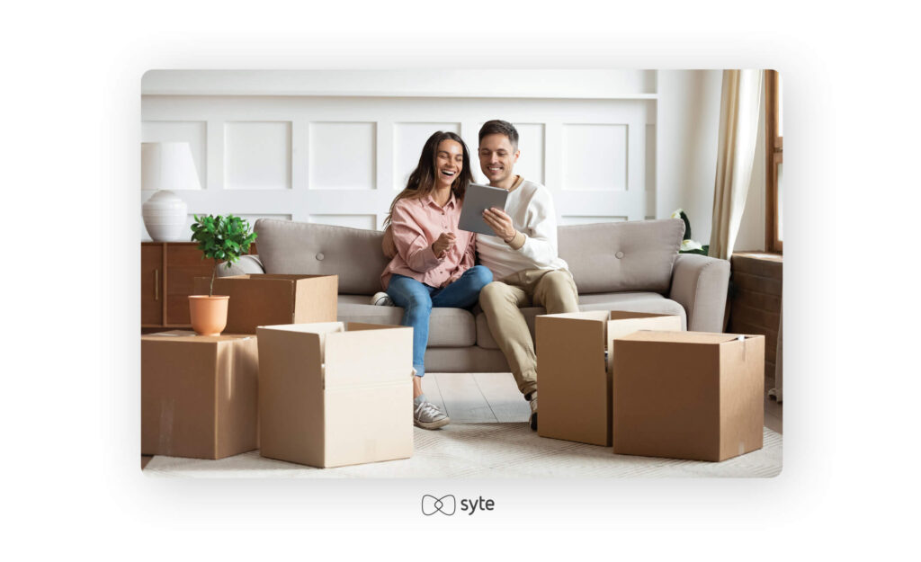 A couple sits on a sofa with a tablet.